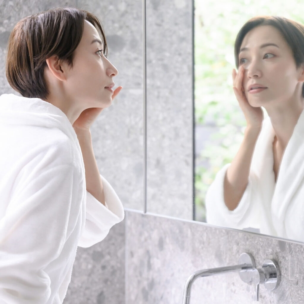 鏡を見て目元を気にしている女性